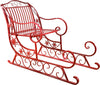 A red metal Christmas sleigh chair with decorative scrollwork and snowflake accents, isolated on a white background.
