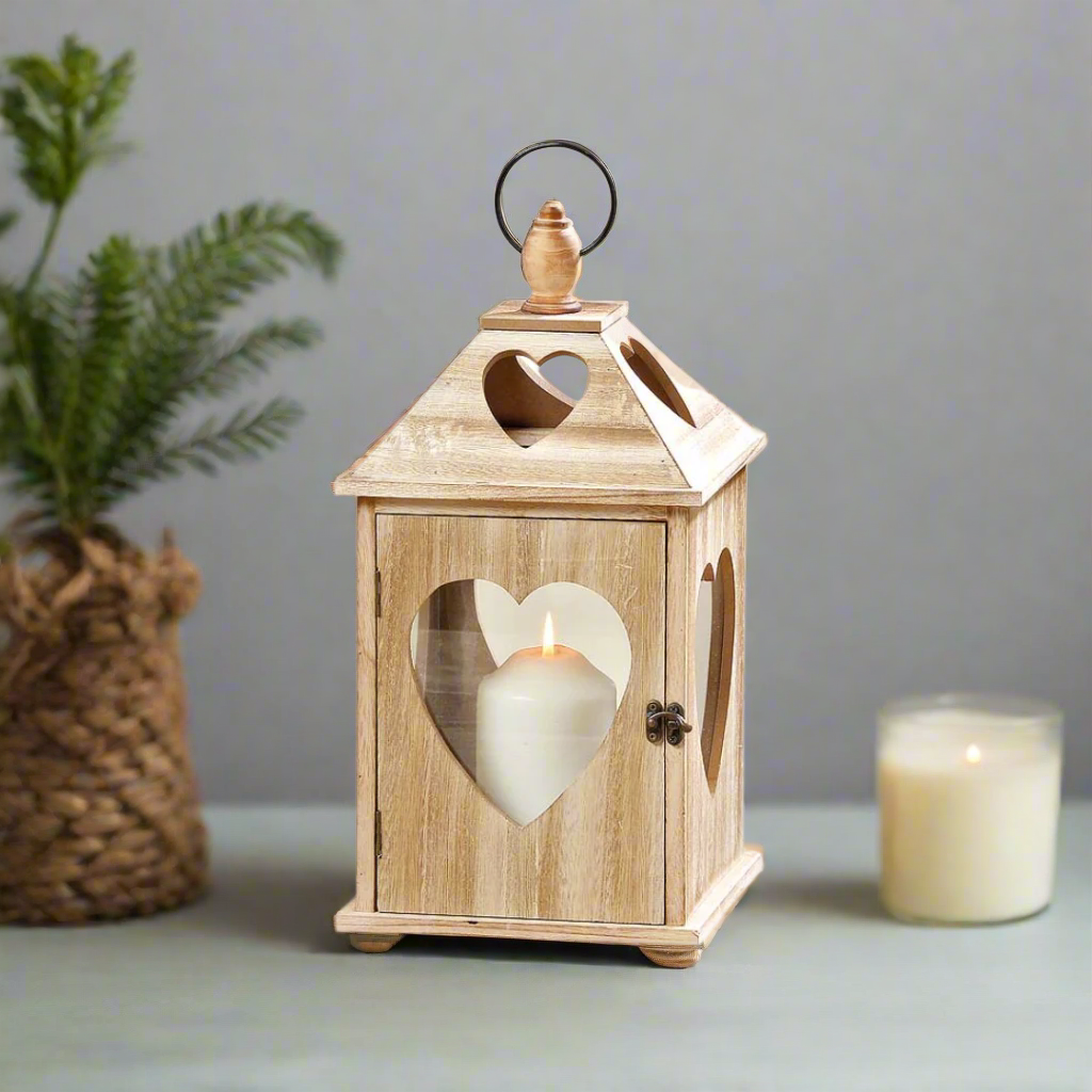 Wooden lantern with a heart-shaped cutout and a lit candle inside on a white background